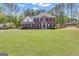 Beautiful two-story red brick home surrounded by a lush green lawn and mature trees at 65 Jacksons Vly, Sharpsburg, GA 30277