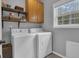 Laundry room with white washer and dryer, wood cabinets, shelving, and natural light from the window at 65 Jacksons Vly, Sharpsburg, GA 30277