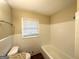 Bathroom featuring neutral wall paint and white tile around the bathtub and toilet, offering a bright and clean aesthetic at 668 Fielding Sw Ln, Atlanta, GA 30311