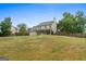Spacious backyard with a home in the background with covered back porch and mature trees at 220 Calli Ct, Mcdonough, GA 30252