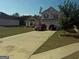 Two-story home boasts a well-manicured front lawn, a long driveway and attached two-car garage at 472 Harvick Cir, Stockbridge, GA 30281