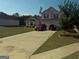 Two-story home boasts a well-manicured front lawn, a long driveway and attached two-car garage at 472 Harvick Cir, Stockbridge, GA 30281