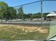Community tennis court with black chainlink fence surrounded by white picket fences and lush green landscape at 5363 Forest Dr, Loganville, GA 30052