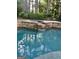 Beautiful backyard pool featuring a stone retaining wall, a small waterfall, and mature trees at 100 Trotters Rdg, Fayetteville, GA 30215
