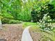 Lush backyard featuring a winding concrete path with mature trees at 2870 Willow Wisp Way, Cumming, GA 30040