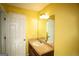 Yellow bathroom featuring a single sink vanity with a mirror and door, perfect for a half-bath at 25 Pacific Ave, Sharpsburg, GA 30277