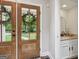 Charming foyer with wood and glass paneled entry doors and a glimpse of the elegant powder room at 400 Peachtree Pkwy, Peachtree City, GA 30269