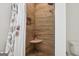 Close-up of a stylish shower with pebble floor, wood-look tile, and a rain shower head at 400 Peachtree Pkwy, Peachtree City, GA 30269