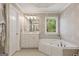 Bright bathroom featuring a corner tub, a vanity, and a decorative leaf-patterned wall at 891 Berryman Pl, Lawrenceville, GA 30045