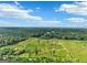 Aerial view of a sprawling estate with a mix of green fields and dense forest under a clear blue sky at 357 Old Driver Rd, Whitesburg, GA 30185