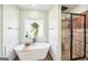 A bright bathroom features a soaking tub, hanging plants, and a walk in shower at 357 Old Driver Rd, Whitesburg, GA 30185