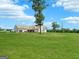 Expansive brick home featuring attached garages, tractor, and a sweeping green lawn on a sunny day at 357 Old Driver Rd, Whitesburg, GA 30185