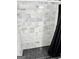 Shower showcases unique black hexagon tile flooring and marble-look tiled walls with a black shower curtain at 441 Lilywood Dr, Mcdonough, GA 30253