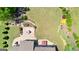Aerial view of a landscaped backyard with a stone patio, hot tub, dining area, and manicured lawn at 266 Blue Point Pkwy, Fayetteville, GA 30215