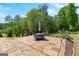 Stone patio with an outdoor dining set and umbrella, surrounded by lush greenery and landscaping at 266 Blue Point Pkwy, Fayetteville, GA 30215
