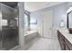 Bathroom featuring a marble-surround tub, a glass shower, dark vanity, and marble floors at 266 Blue Point Pkwy, Fayetteville, GA 30215