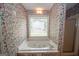 Bathroom with floral wallpaper featuring a tiled shower and soaking tub with a window at 250 Clearview Cir, Mcdonough, GA 30253