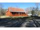 Cozy red cabin featuring a covered porch, a metal roof, and an adjacent gravel driveway at 526 Mount Carmel Church Rd, Temple, GA 30179