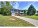 Beautiful front of a brick home with a long driveway, green lawn, and vibrant surrounding trees at 130 Belmont Farms Dr, Ellenwood, GA 30294