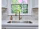 Modern kitchen sink with gold faucet and white countertops, complemented by a bright window view at 130 Belmont Farms Dr, Ellenwood, GA 30294