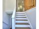 Bright staircase leading to the kitchen area, featuring white risers and wood treads at 130 Belmont Farms Dr, Ellenwood, GA 30294