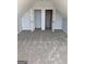 Unfinished attic space with neutral walls and carpet and two large closets at 563 Deadwood Trl, Locust Grove, GA 30248