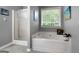 Well-lit bathroom featuring a large tub, separate shower, and neutral-toned walls and tile at 563 Deadwood Trl, Locust Grove, GA 30248