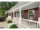 Charming front porch with white columns, an American flag, rocking chair and lush shrubs at 563 Deadwood Trl, Locust Grove, GA 30248