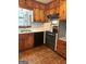 Kitchen featuring knotty pine cabinets with black appliances and brick-patterned flooring at 6576 Randall Mark Dr, Morrow, GA 30260
