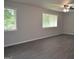 Spacious living room with grey plank flooring, neutral paint, and ample natural light from two large windows at 6286 Saddlewood Dr, Lithonia, GA 30058