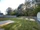 View of the backyard with a chain link fence, fire pit, shed, and a forested backdrop at 127 Jenny Rd, Grantville, GA 30220