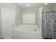 Bright bathroom featuring a large tiled jacuzzi tub with a window at 1231 Hillview Rd, Hampton, GA 30228