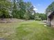 Spacious backyard with a large grassy area, mature trees, and a partial view of the home's exterior at 110 Thompson Blvd, Stockbridge, GA 30281