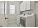 Laundry room with white washer and dryer, tile floors, and white cabinetry above the units at 307 Owenberg Trce, Peachtree City, GA 30269