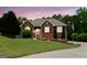 Charming red brick home with manicured lawn, mature trees, under a beautiful twilight sky at 1112 Haver Ct, Mcdonough, GA 30252