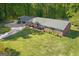 Aerial view of a brick ranch home with an expansive, green front lawn and mature trees at 118 Duvall Dr, Stockbridge, GA 30281