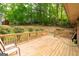 Wide angle view of a wooden back deck with chairs, red barn and surrounding green trees at 215 Ridge Rd, Tyrone, GA 30290