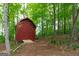 Red outbuilding with double doors and small deck in a lush, tree filled backyard at 215 Ridge Rd, Tyrone, GA 30290