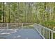 View of the gray back deck overlooking wooded backyard with a white railing at 110 Greenridge Ct, Fayetteville, GA 30215