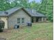 Back view of the home, featuring a brick facade, lush green yard, mature trees, and a covered porch at 678 Oak Grove Rd, Mcdonough, GA 30253