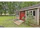 Exterior view of the backyard shed with red doors and a ramp, on a green lawn under shade trees at 215 Calgary Dr., Peachtree City, GA 30269