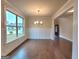 Elegant dining area with hardwood floors, wainscoting, a modern chandelier, and a large window for natural light at 542 Hinton Farm Way, Dacula, GA 30019
