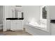 Bright bathroom featuring a soaking tub and a dual sink vanity with black countertop at 3219 Broadnax Mill Rd # 5, Loganville, GA 30052