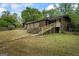 Backyard featuring a stone and wood exterior with modern stairs, complemented by a lush green lawn at 5493 Alexanders Lake Sw Rd, Stockbridge, GA 30281