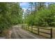 Gated driveway leading through a lush green forest, creating a private and scenic entrance to the property at 5493 Alexanders Lake Sw Rd, Stockbridge, GA 30281