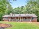 Charming brick home featuring a welcoming front porch, well-manicured lawn, and mature trees at 930 Singley Dr, Locust Grove, GA 30248