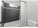 Modern bathtub featuring dark tile surround, shower curtain, and crisp white toilet at 105 Riviera Ct, Fayetteville, GA 30215