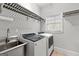 Modern laundry room features a stainless steel sink and front loading washer and dryer at 105 Riviera Ct, Fayetteville, GA 30215