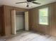 Bedroom featuring wood paneling, wood-look laminate flooring, a closet with open doors, and a window at 8833 Thomas Rd, Jonesboro, GA 30238