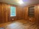 Bedroom featuring wood-paneled walls, hardwood floors, a window, and a built-in shelving unit at 8833 Thomas Rd, Jonesboro, GA 30238